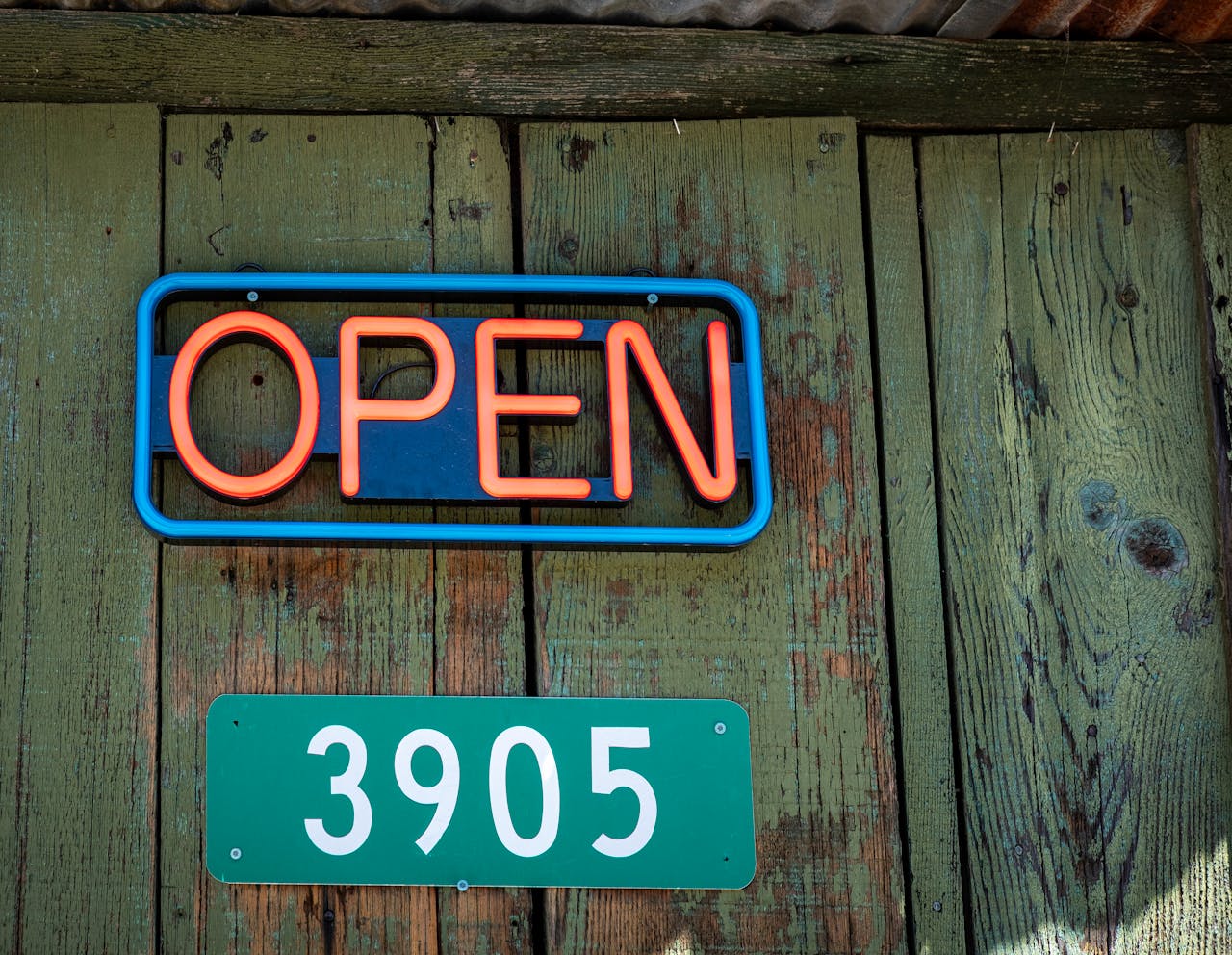 A neon sign that says open on a wooden door